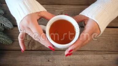 妇女手拿茶匙，在木桌上搅拌热茶，背景是南瓜、树叶、香料。秋季大会